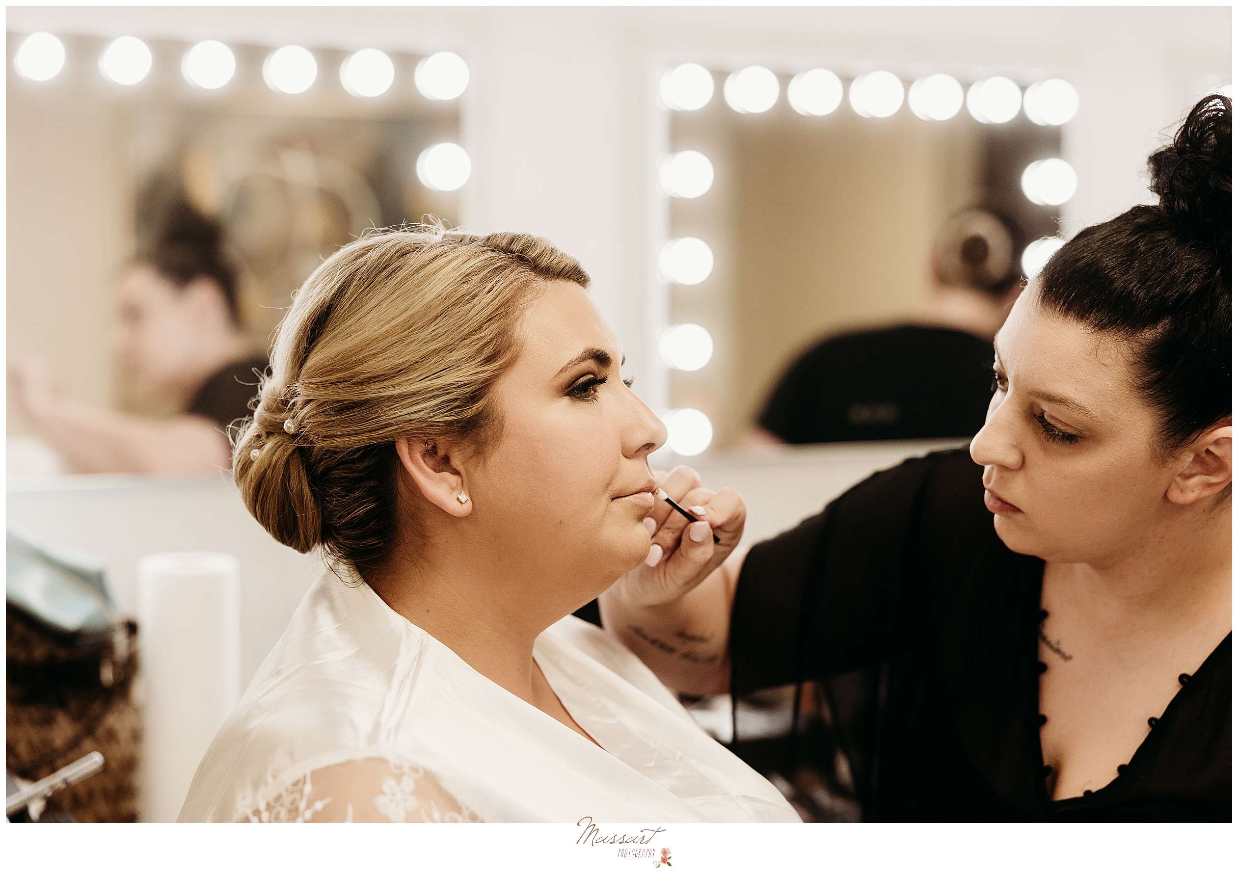 woman in black shirt puts on lip gloss for bride on RI wedding day