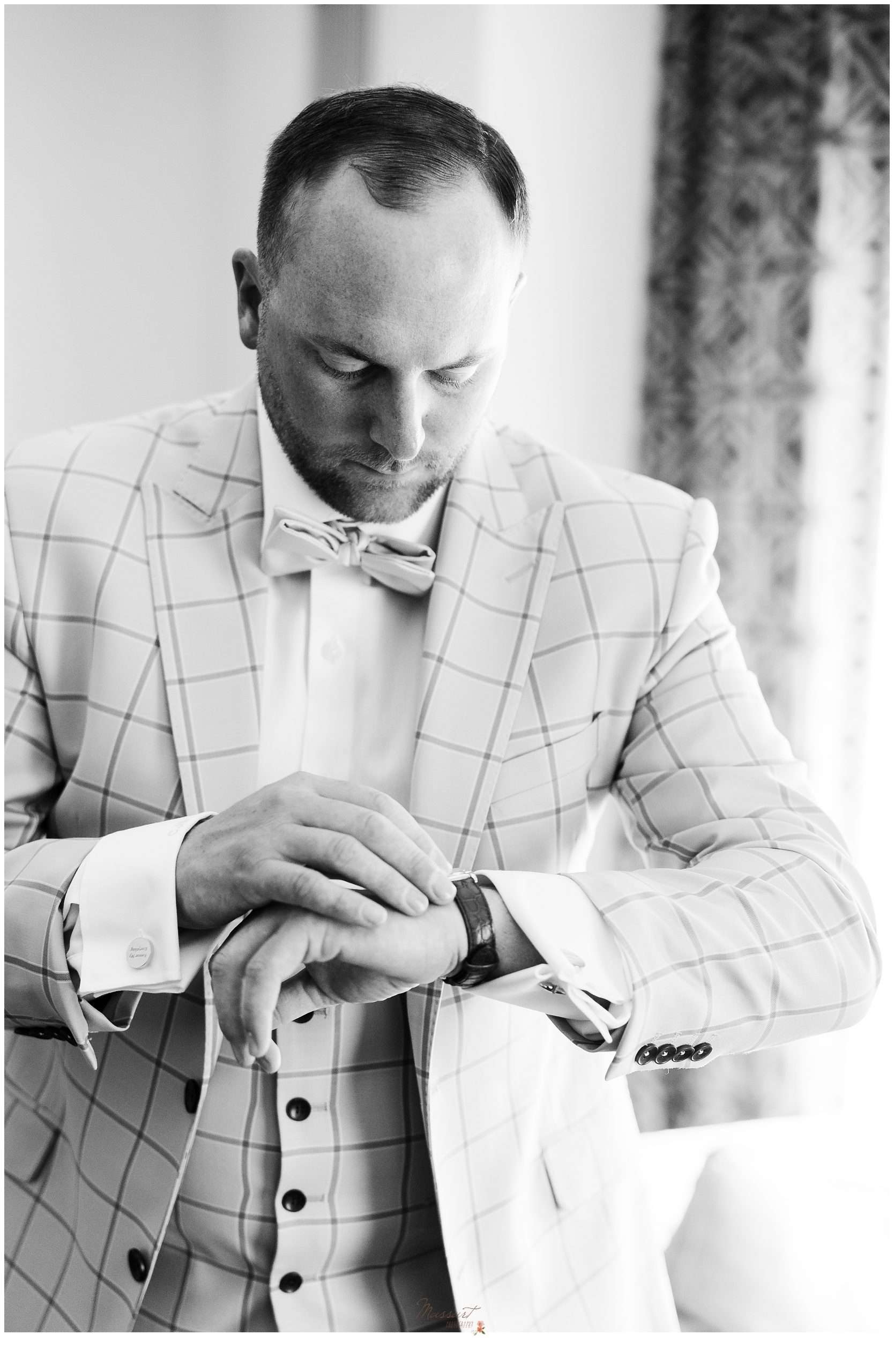 groom adjusts watch in plaid suit on morning of Rhode Island wedding day