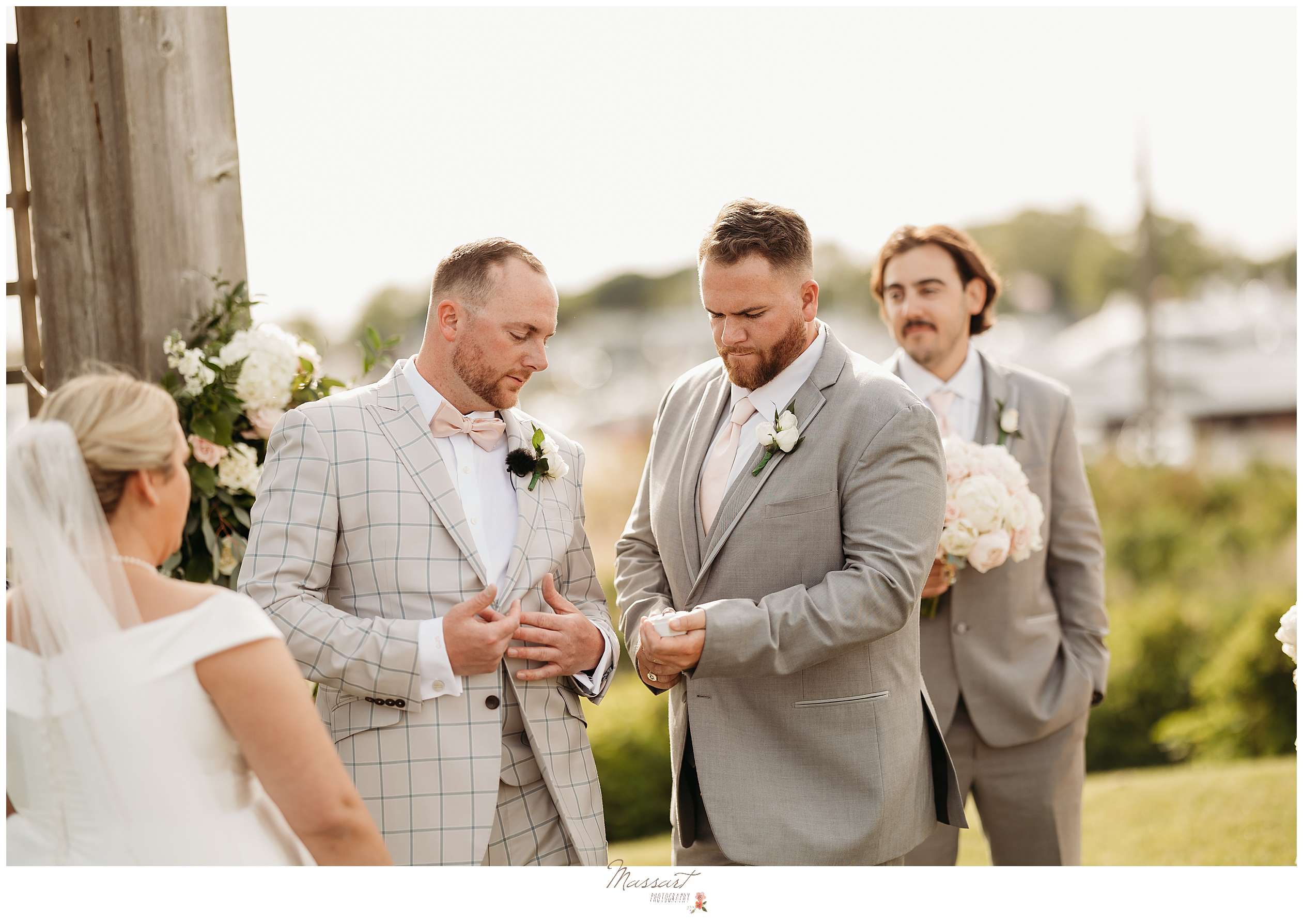 groomsman gives groom rings during wedding ceremony along waterfront at Harbor Lights
