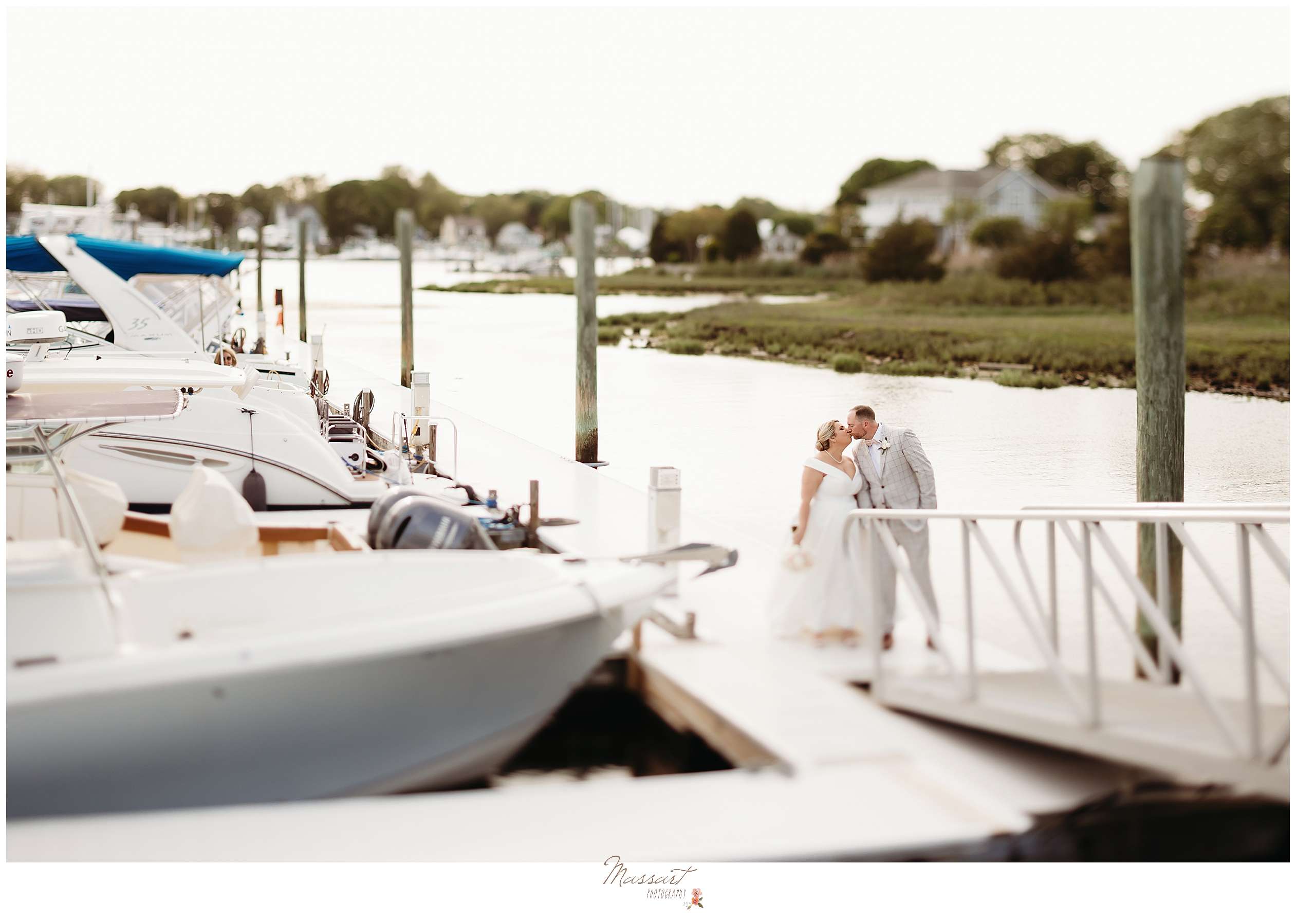 newlyweds kiss at end of dock of marina outside Harbor Lights