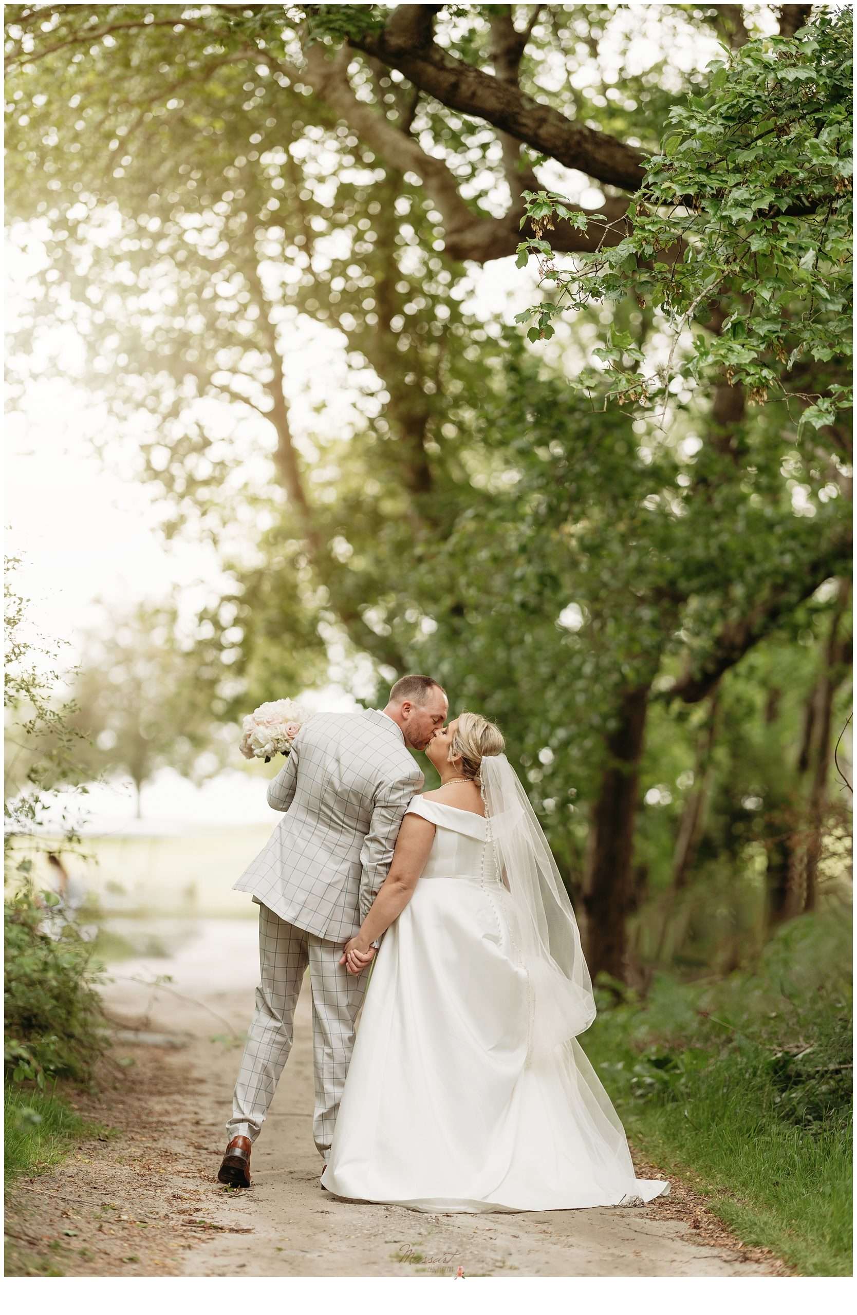 bride and groom kiss on pathway outside Harbor Lights at sunset