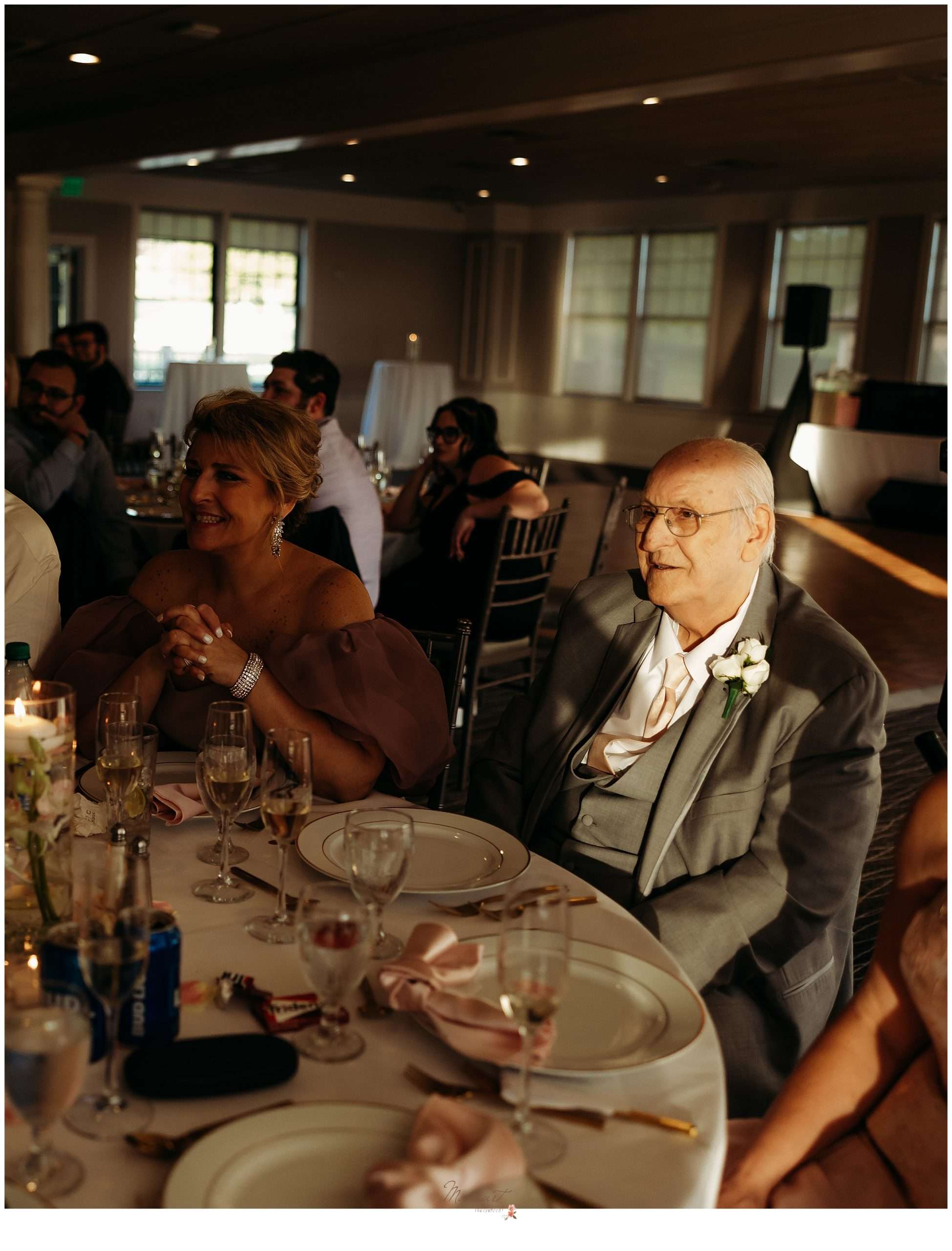 old man sits at reception table listening to toasts